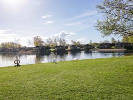 A lake with swans and cabins at Borwick Heights 17 in Carnforth
