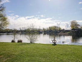 A scenic view of a lake with swans and cabins at Borwick Heights 17 in Carnforth
