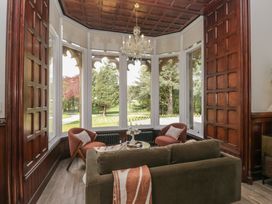 A living room with a sofa and armchairs and large windows at Brettargh Holt Mansion near Levens