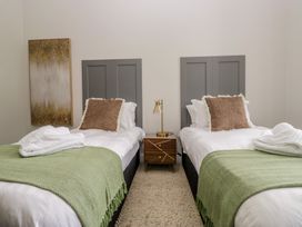 A bedroom with two beds and a bedside table at Brettargh Holt Mansion near Levens