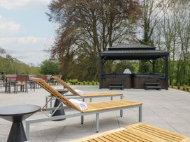 An outdoor patio with sun loungers and a hot tub at Brettargh Holt Mansion near Levens
