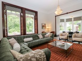 A living room with a green sofa and a glass table at Brettargh Holt Mansion Sleeping 48 near Sizergh, Cumbria