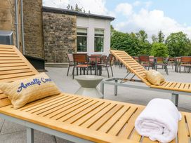 An outdoor area with sun loungers and a table at Brettargh Holt Mansion Sleeping 48 near Sizergh, Cumbria