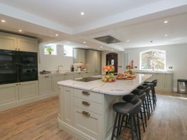 A kitchen with an island, bar stools, and appliances at Brettargh Holt Mansion 32 near Levens