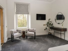 A living room featuring two chairs, a television, table and plant at Brettargh Holt Mansion 32 near Levens