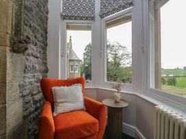 A snug with an orange armchair and side table at Brettargh Holt Mansion 32 near Levens
