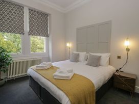 A bedroom with a bed, bedside table and windows at Brettargh Holt Mansion 32 near Levens