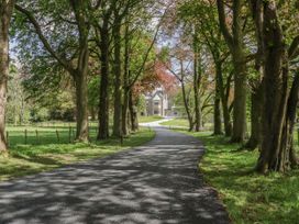 A driveway lined with trees leading to a house at Brettargh Holt Mansion 32 near Levens