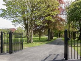 A black gate opening onto a tree-lined road at Brettargh Holt Mansion 32 near Levens