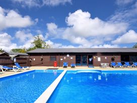 An outdoor swimming pool with sun loungers at Hazelwood 3 in Pinewood Retreat in Rousdon near Lyme Regis
