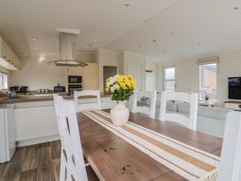 A kitchen with a dining table and flowers at Hazelwood 3 Pinewood Retreat in Rousdon near Lyme Regis