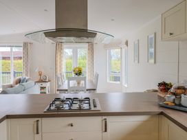 A kitchen with a stove and dining area at Hazelwood 3 Pinewood Retreat in Rousdon near Lyme Regis