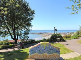 A coastal view from a park with trees and a mosaic seat at Hazelwood 3 in Pinewood Retreat in Rousdon near Lyme Regis