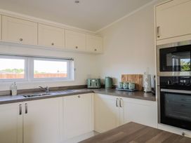 A kitchen with a sink, cabinets, and appliances at Hazelwood 3, Pinewood Retreat in Rousdon near Lyme Regis