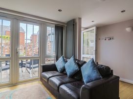 A living room with a sofa and sliding doors leading to outdoor seating at Beck House Weymouth