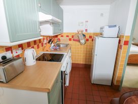 A kitchen featuring a sink, stove, refrigerator, and various utensils at Warbler Cottage in Cowbridge