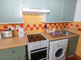 A kitchen with appliances and cabinets at Warbler Cottage in Cowbridge