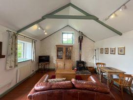 A living room with a sofa, table, and fireplace at Warbler Cottage near Cowbridge