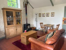 A living room with a sofa, table, and fireplace at Warbler Cottage near Cowbridge