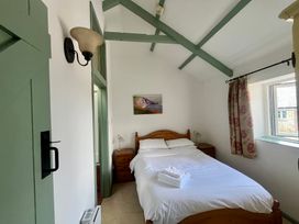 A bedroom with a bed and window at Warbler Cottage near Cowbridge