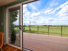A balcony view with a glass door overlooking a green field at Freedom Lodge @ Summerfield Farm, Whitby