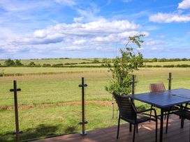 A patio with a table and chairs overlooking a grassy field at Freedom Lodge @ Summerfield Farm Whitby