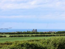 A view of the sea and buildings surrounded by fields at Freedom Lodge @ Summerfield Farm in Whitby