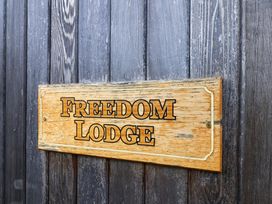 A wooden sign displaying Freedom Lodge at Freedom Lodge @ Summerfield Farm in Whitby