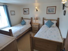 A bedroom with twin beds and a nightstand at Trelake Cottage