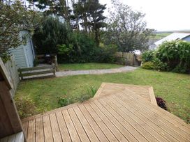 A garden with grass, decking, and a pathway at Trelake Cottage