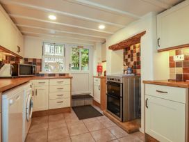 A kitchen with various appliances and a door at Trelake Cottage in Tintagel