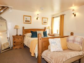 A bedroom with a bed and a mirror at Trelake Cottage in Tintagel