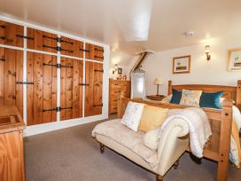 A bedroom with a bed, sofa, drawers and wardrobe at Trelake Cottage in Tintagel