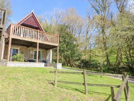 A building with a balcony surrounded by grass and trees at Honeycombe Lodge