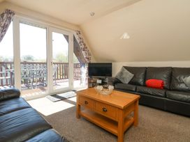 A living room with a coffee table and television at Honeycombe Lodge