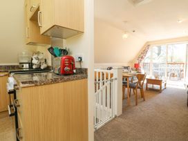 A kitchen with cabinets and a dining area at Honeycombe Lodge