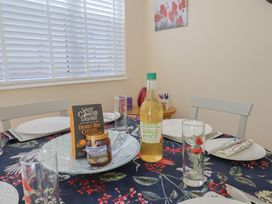 A dining table set with plates, glasses, cheese, honey, and apple juice at Tane in Winterborne Stickland