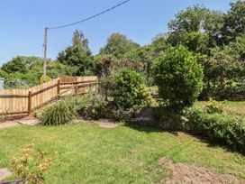 A garden with grass and a wooden fence at Tane in Winterborne Stickland