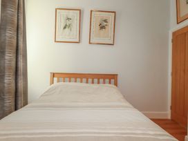 A bedroom with a bed and framed pictures at Farthings, The Old Chapel in St Austell