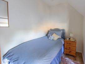A bedroom with a bed and nightstand at Honeypot Cottage in Weymouth