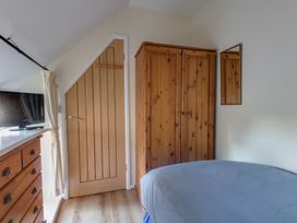 A bedroom with a bed, wardrobe, and television at Honeypot Cottage in Weymouth