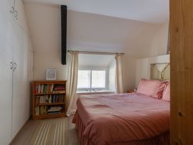 A bedroom with a bed and bookshelf at Honeypot Cottage in Weymouth