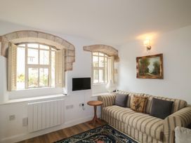 A living room with a sofa, table, and windows at Longfords Mill near Nailsworth