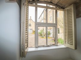 A window with shutters overlooking a courtyard at Longfords Mill near Nailsworth