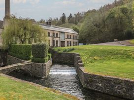 A building beside a stream and bridge at Longfords Mill near Nailsworth