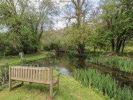 A bench near a river surrounded by trees and plants at Longfords Mill near Nailsworth
