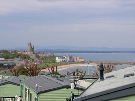 A beach view with a castle in the background at 18 Eden Heights in St Andrews