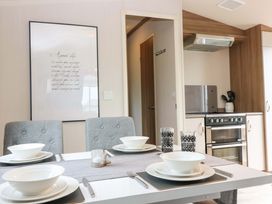 A dining room with table set for dinner and kitchen appliances at 18 Eden Heights in St Andrews