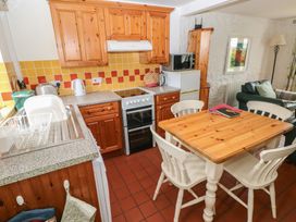 A kitchen with wooden cabinets and a dining table at Swallow Cottage in Cowbridge