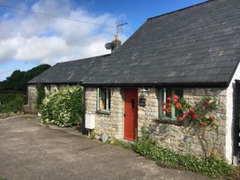 A cottage with a red door and plants at Swallow Cottage near Cowbridge